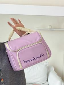 Pink ballet-style bow cosmetic bag with top handle and embroidery in a lifestyle setting