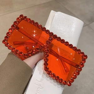 Detail of red rhinestone-encrusted oversized square sunglasses with orange lenses
