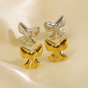 Minimalist 14K gold and silver bow heart stud earrings set on elegant silk background