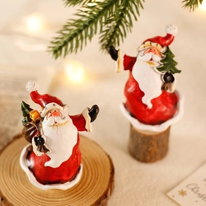 Miniatur-Weihnachtsmann-Figuren auf Holzsockel mit festlicher Tanne und warmem Hintergrund