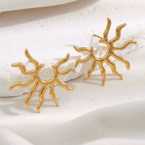 Detail shot of golden sunburst earrings on minimalist stone surface with soft lighting