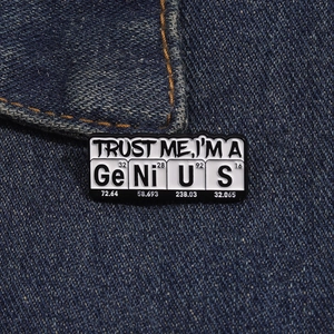 Close-up of Trust Me I'm a Genius science pin with periodic table elements on blue denim
