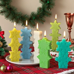 Five colored snowflake stack candles with lit wicks on festive Christmas table setting