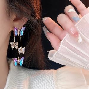 Macro shot of long butterfly tassel earrings featuring iridescent purple and clear crystals
