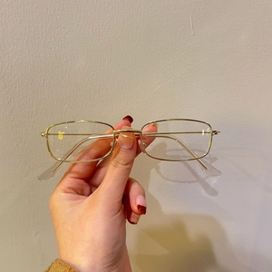 Detailed close-up of retro rectangular gold metal frame sunglasses with clear lenses
