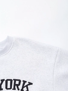Detail of light grey sweatshirt featuring black YORK embroidery and ribbed neckline