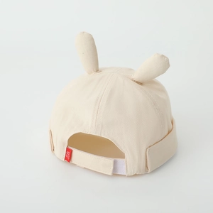 Detail view of adjustable velcro strap and cute rabbit ears on cream baby hat
