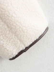 Detailansicht von flauschigem cremefarbenem Fleece mit dunkelbraunem Kunstlederbesatz
