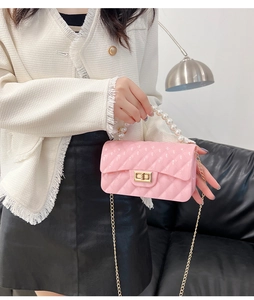 Detail of pink jelly bag featuring a pearl handle, quilted texture, and gold chain strap