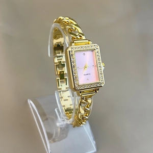 Detail of a square gold watch with pink dial and diamond-set bezel on a chain strap