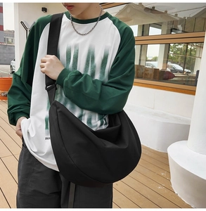 Close-up of a large black crescent oxford cloth crossbody bag worn by a male model