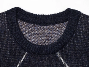 Detail view of the ribbed round neckline and diamond pattern on navy knit sweater