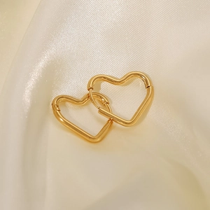 Macro detail of interlocked 18K gold plated heart earrings on elegant silk background