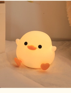 Detailed close-up of a glowing yellow silicone duck night light on a white desk