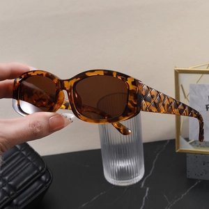 Detail of tortoise shell sunglasses with diamond pattern carving on thick oval frame