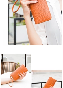 Detail view of bright orange crocodile embossed texture clutch bag with wristlet