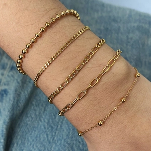 Ensemble de cinq bracelets en acier inoxydable doré superposés sur un poignet humain