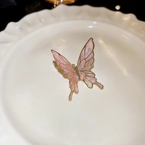 Detailed macro view of pink butterfly ear cuff with golden edges on white ceramic plate