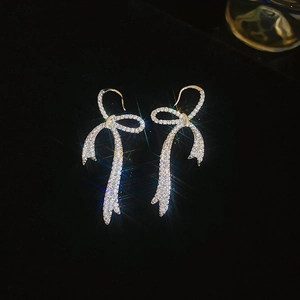 Detailed macro of silver bow earrings with sparkling cubic zirconia on black velvet