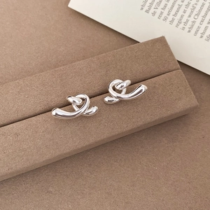 Vue détaillée des boucles d'oreilles torsadées en métal argenté sur un support décoré