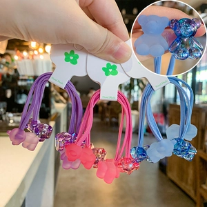Detail of three gummy bear hair ties in purple pink and blue with matte resin charms