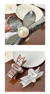 Detailed close-up of hair claws with marble textures and pearl accents on a wooden desk