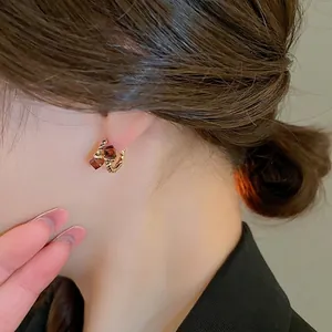 Elegant gold plated twist earrings with square amber zircon worn by a fashion model