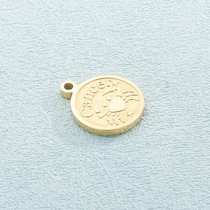 Detailed view of a gold Cancer zodiac pendant featuring an engraved crab and lettering