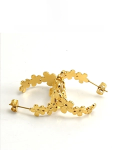 Macro detail of gold-plated daisy flower C-shaped hoop earrings with polished finish