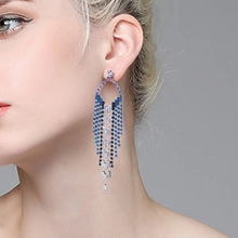Close-up of elegant long tassel earrings with blue and clear crystals on a female model