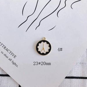 Detail of round enamel pendant with Eiffel Tower relief and black and white pattern
