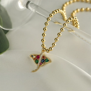 Macro detail of a gold manta ray pendant with colorful pave-set zircon crystals