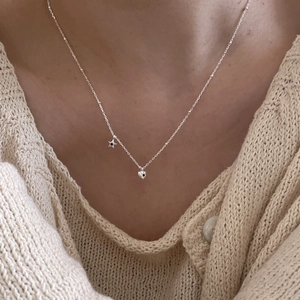 Close-up of 925 sterling silver necklace with star and heart charms on knitted sweater