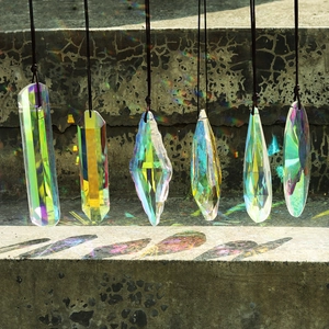 Set of six varied AB crystal suncatchers casting rainbow reflections on concrete