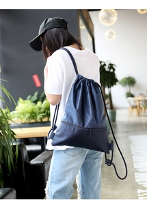 Navy nylon drawstring backpack with honeycomb texture shown on a model in a cafe