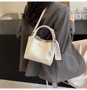 Close-up of white lychee pattern leather bucket bag with elegant grey checkered silk scarf