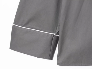 Detailed close-up of dark grey poplin shirt sleeve and hem with white piping trim