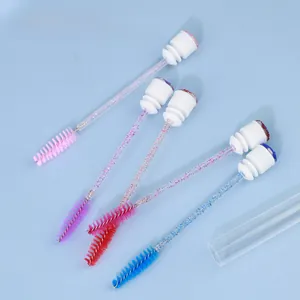 Macro detail of five disposable mascara brushes with glitter handles on blue background