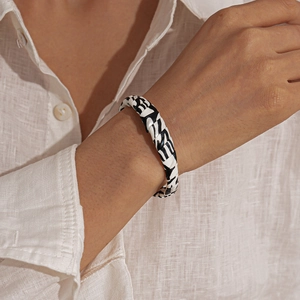 Close-up of black and white woven faux leather cuff bracelet on a model's wrist