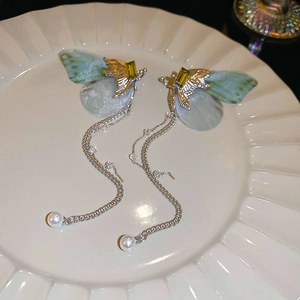 Gros plan de boucles d'oreilles ailes de papillon avec de longs glands et des perles