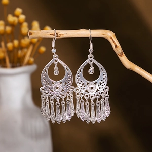 Detail of silver bohemian dangle earrings with hollow geometric patterns and teardrop tassels