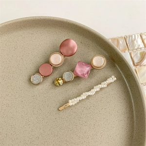 Detailed view of three pearl hair clips with pink glitter resin and gold alloy star patterns