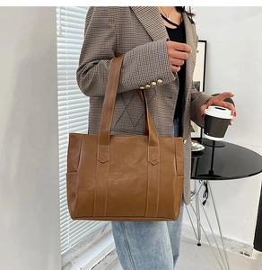 Brown PU leather tote bag with vertical stitching shown in a professional office setting