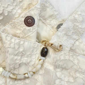 Détail du sac en dentelle blanc cassé avec fermoir magnétique et chaîne perlée colorée
