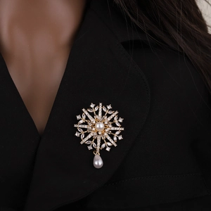 Elegant gold snowflake brooch with pearls and crystals pinned on a black coat lapel