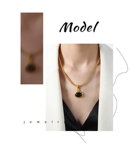 Detail of gold snake chain necklace with black oval gemstone on professional model