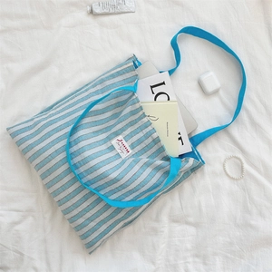 Dettaglio della borsa tote in tela a righe blu con manici blu vivace e logo in tessuto