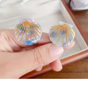 Detailed view of two shell-shaped hair clips with iridescent pastel colors and gold relief
