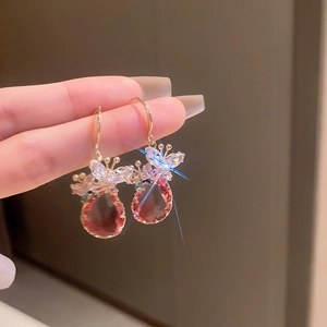 Détail de boucles d'oreilles papillon dorées avec pierres rouges en forme de goutte