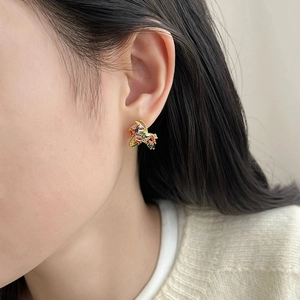 Close-up of gold plated stud earrings with colorful rectangular zircons worn by a model